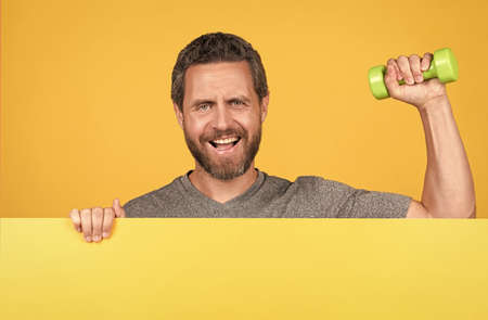 Weight training. Sportsman hold dumbbells yellow background.の写真素材