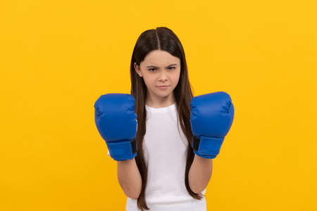 aggressive child in boxing gloves on yellow backgroundの写真素材