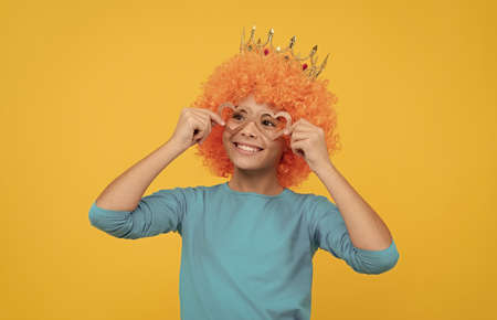 happy funny kid in curly wig and crown. imagine herself a queen. cheerful child wear diadem