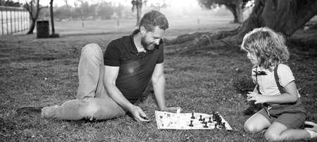 father and son play chess on grass in summer park, chessの写真素材