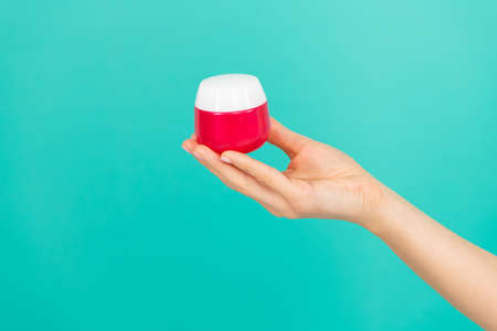 female hand hold skin cream on blue backgroundの写真素材