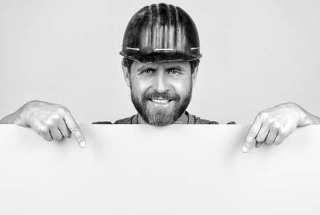 presenting novelty information. bearded worker in hardhat behind yellow paper sheet.の写真素材