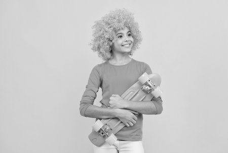 skateboarding. cheerful child holding penny board. teen girl with fancy hairstyle. being a clownの写真素材