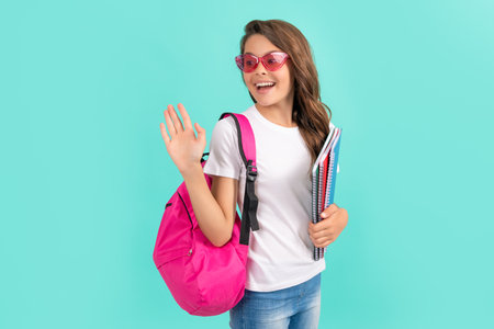 happy teen girl with backpack and copybook ready to study at school waving hello, school