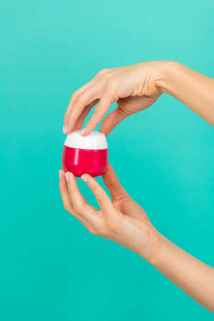 female hands hold moisturizing skin cream on blue backgroundの写真素材