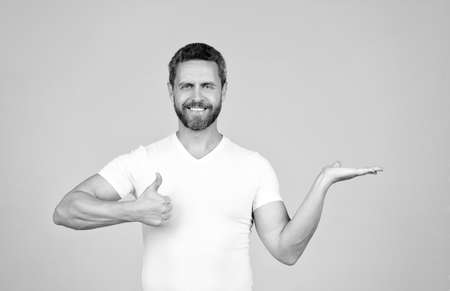 Presenting the best product. Happy man give thumbs-up showing open hand. Presenting productの写真素材