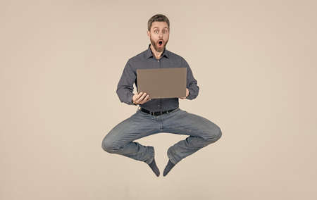 surprised energetic jumping man businessman while working online on laptop, saleの写真素材