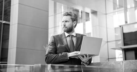 serious bearded businessman in formal suit working online on laptop, success