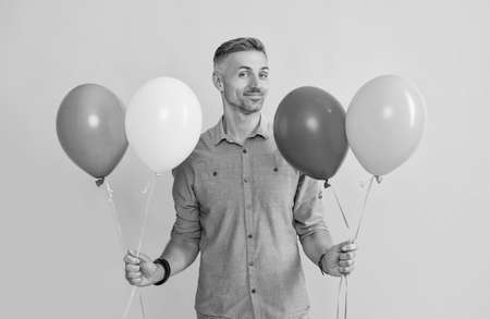 smiling handsome man hold balloons on yellow background, holidayの写真素材