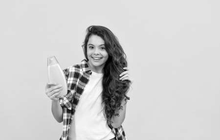 presenting cosmetic product. beauty. kid use shower gel. happy teen girl with shampoo bottle.の写真素材