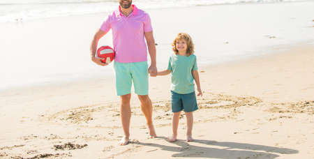 cropped father and son walk with ball on beach. daddy with kid boy on summer day.の写真素材