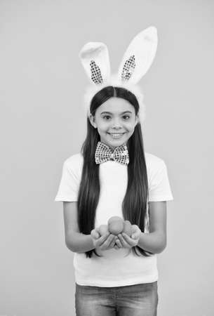 happy easter kid girl in bunny ears and bow tie hold painted eggs, egg huntの写真素材