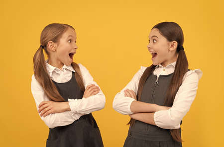 Surprised little kids look at each other with open mouths in formal school uniforms, surpriseの写真素材