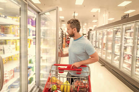 man with shopping cart buying food at grocery, consumptionの写真素材