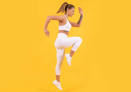 fitness coach woman jumping on yellow background