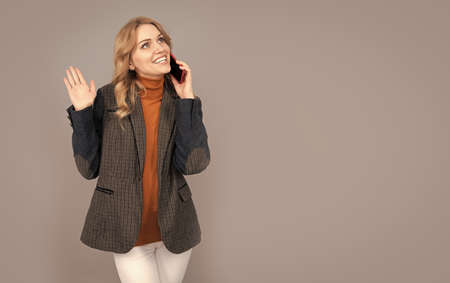 Happy woman in casual fashion style talk on mobile phone grey background copy space, conversation
