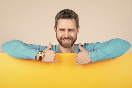 happy man behind blank paper banner with copy space for announcement show thumb up, creativity.
