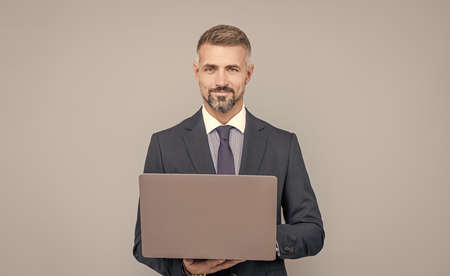 mature manager with grizzled hair in formal suit working on computer online, freelancer