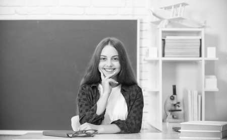 happy kid sitting in classroom at blackboard, schoolの写真素材