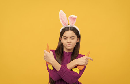 serious teen child in bunny ears holding carrot, easter holiday