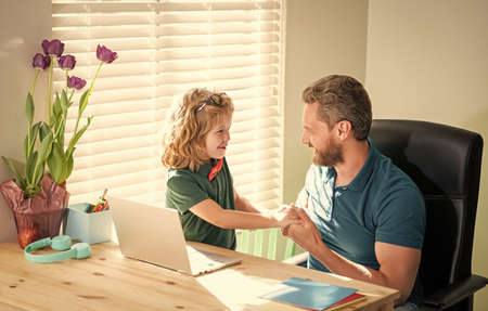 happy dad helping his school son child in glasses study with computer at home, family
