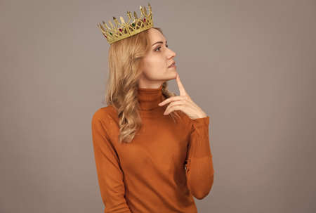 thinking blonde girl with curly hair wear crown, imagineの写真素材