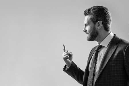 Professional man in suit sideway keep finger pointing up grey background copy space, ideaの写真素材