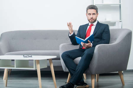 amazed mature businessman in suit sit in office with planner