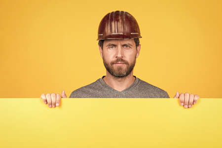 mature man in helmet. builder with copy space on paper. presenting novelty information.の写真素材