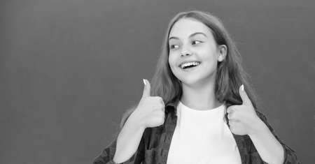 happy teen girl showing thumb up at blackboard, emotions