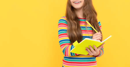 Happy school kid learn to write with eyes closed yellow background, homeworkの写真素材