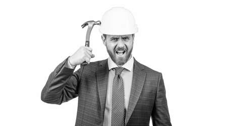 confident businessman man in suit hit safety helmet with hammer isolated on white, protectionの写真素材
