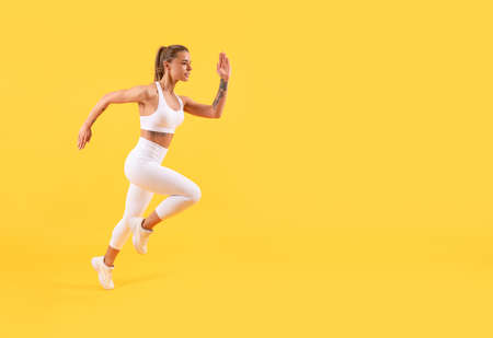 fitness girl runner running on yellow background with copy spaceの写真素材