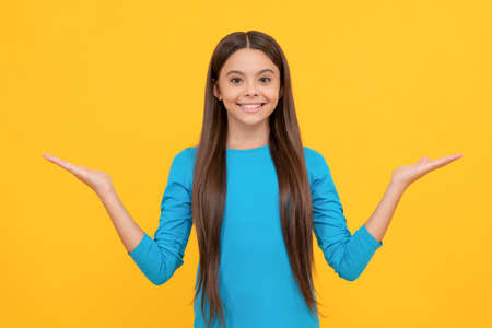 happy teen girl with long hair making choice on yellow background with copy space, choiceの写真素材