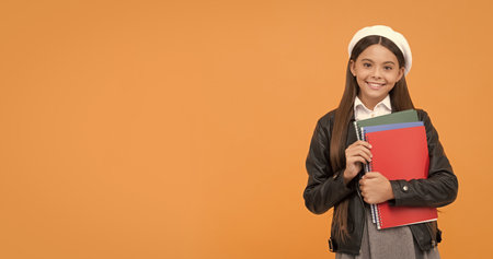 Happy school age girl child hold books September 1 orange background copy space, back to schoolの写真素材