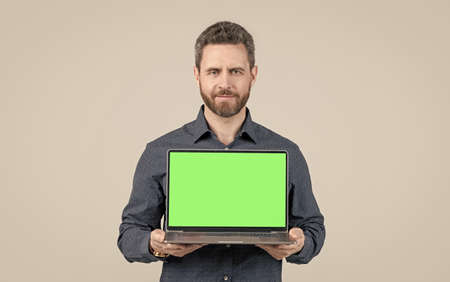 cheerful bearded man showing green laptop screen for video presentation, copy space, modern lifeの写真素材