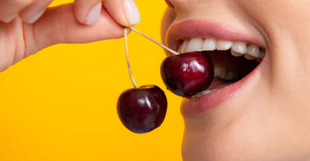 Womans enjoying fresh sweet cherry. Female mouth eating sweet cherry. Closeup female mouth tasting sweet cherry.の写真素材