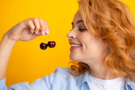 Woman with cherry, organic fruits. Cherries and harvesting in summer. Girl picking and eating ripe cherries, fresh fruits. Healthy organic berry cherry fruit, summer harvest season.の写真素材