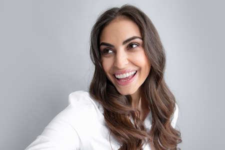 Close-up of young beautiful woman taking selfie. Isolated gray background. Portrait of cool cheerful...