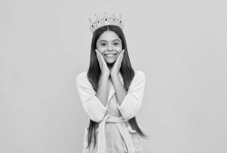 smug happy teen girl in home terry bathrobe and princess crown, smugnessの写真素材