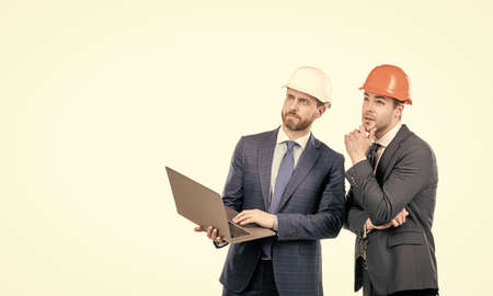businessmen in helmet with laptop. architects planning work. chief engineer and executive in hardhat