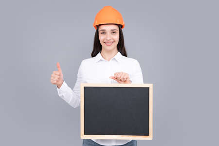 Smiling woman builder in helmet holding board for advertising sign. Sign board with copy space.の写真素材