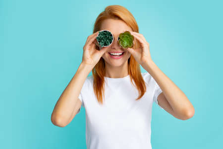 Young beautiful woman holding cactus pot over isolated blue background.の写真素材