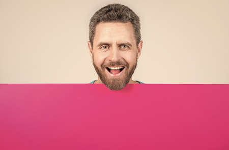 happy mature bearded man behind blank pink paper banner with copy space for info, saleの写真素材
