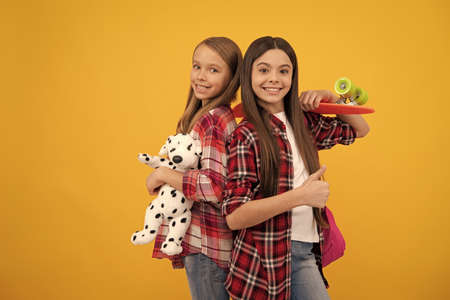 happy teen girls in casual checkered shirt carry backpack toy and penny board, skateboardの写真素材