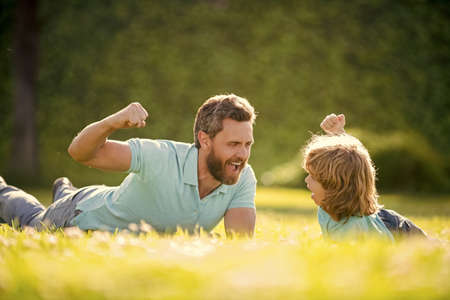 parent relax with little child boy on grass. glad dad with kid on summer day.の写真素材