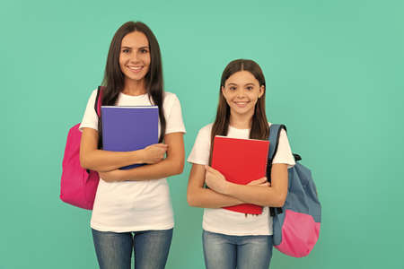 happy daughter pupil and mother or teacher hold school workbook for studying, back to schoolの写真素材