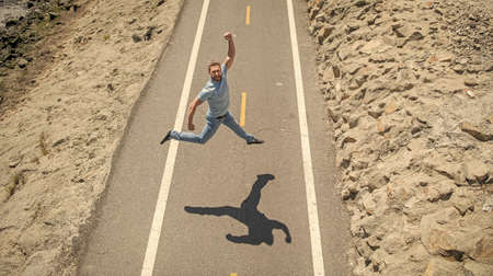 happy mature athletic guy jumping on road outdoor, emotionsの写真素材