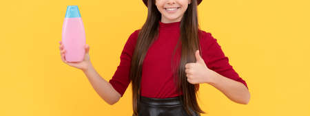 thumb up. happy girl in hat hold shampoo. presenting cosmetic product for teen.