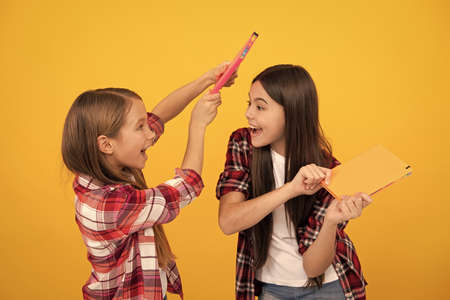 cheerful children in casual checkered shirt having fun with notebooks, best friendの写真素材